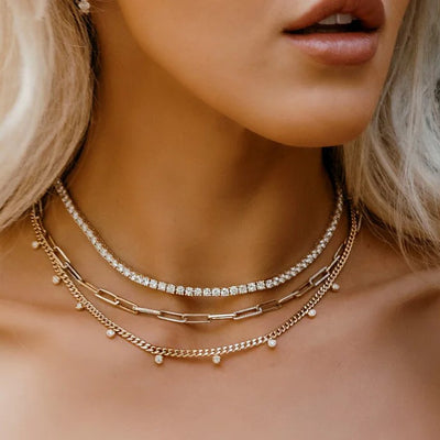 a woman wearing layered gold and diamond necklaces