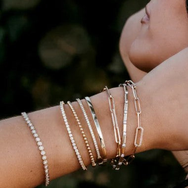 A woman wearing a stack of gold and diamond bracelets