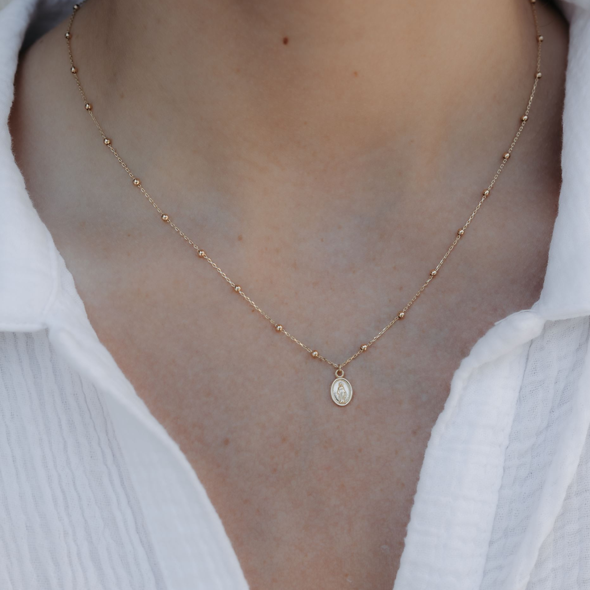 Mary medallion and gold bead necklace